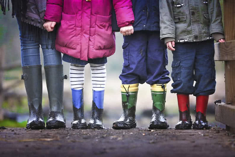 Kinder in Gummistiefeln auf Klassenfahrt